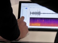 ein Finger tippt auf einen Bildschirm, dort sieht man die Grafik einer Erschütterungsmessung